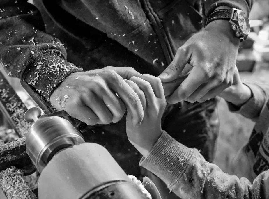 Mains guidant un geste de tournage sur un tour à bois